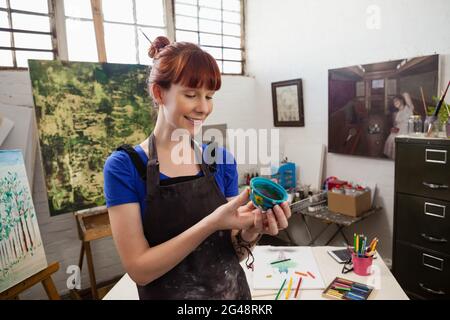 Schöne Frau, die bemalte Schüssel ansieht Stockfoto