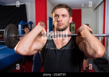 Junger männlicher Athlet, der die Langhantel durch einen Boxring hebt Stockfoto