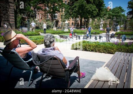 Besucher spielen eine Partie Schach auf dem Schachbrett im Garten. . Stockfoto