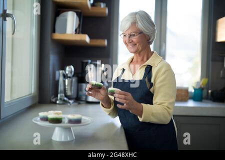 Ältere Frau holt den Cupcake vom Tablett Stockfoto