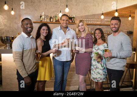 Glückliche Freunde stehen mit Getränken im Restaurant Stockfoto