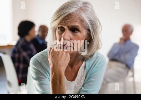 Angespannte ältere Frau mit Freunden im Hintergrund Stockfoto