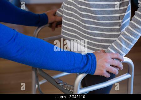 Physiotherapeut, der dem Patienten beim Gehen mit Gehrahmen hilft Stockfoto