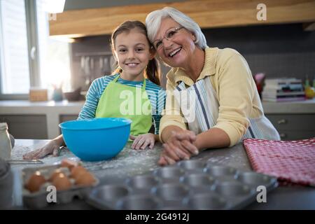Enkelin und Großmutter posieren, während sie in der Küche stehen Stockfoto