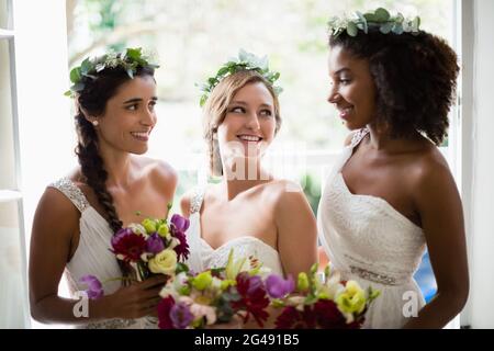 Braut und Brautjungfern stehen mit Blumenstrauß Stockfoto