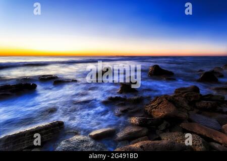 Surfen und Gezeiten auf den Sandsteinfelsen von Newport Beach, den nördlichen Stränden von Sydney - malerischer Sonnenaufgang am Meer. Stockfoto