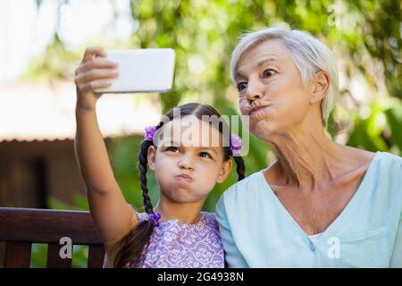 Mädchen und Großmutter machen Gesichter beim Selfie Stockfoto