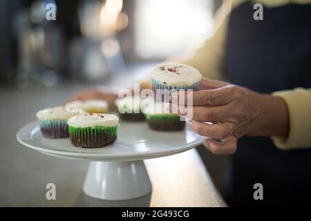 Ältere Frau holt den Cupcake vom Tablett Stockfoto