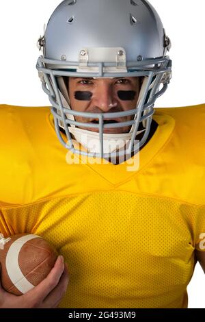 Porträt eines entschlossenen amerikanischen Fußballspielers, der den Ball mit einem Helm hält Stockfoto