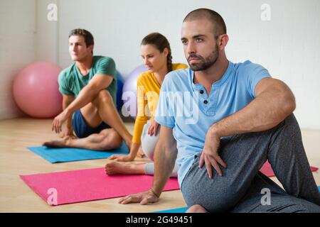 Yogalehrer führt die Schüler beim Üben von Ardha Matiendrasana Stockfoto