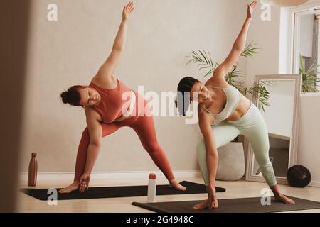Frauen, die eine Yoga-Routine im Fitnessstudio durchführen. Fitness-Frau, die Dreieck-Yoga-Pose macht. Stockfoto