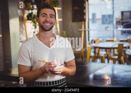 Porträt eines lächelnden Kellners, der die Bestellung annahm Stockfoto