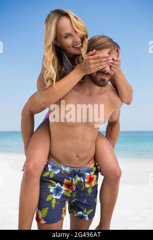 Mann Huckepack fröhliche Frau am Strand Stockfoto