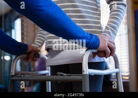 Physiotherapeut, der dem Patienten beim Gehen mit Gehrahmen hilft Stockfoto