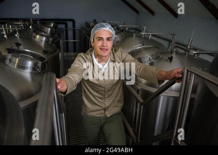 Porträt eines Arbeiters, der auf einer Treppe inmitten von Lagertanks steht Stockfoto