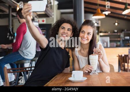 Glückliches Paar, das Selfie macht, während es im Restaurant sitzt Stockfoto