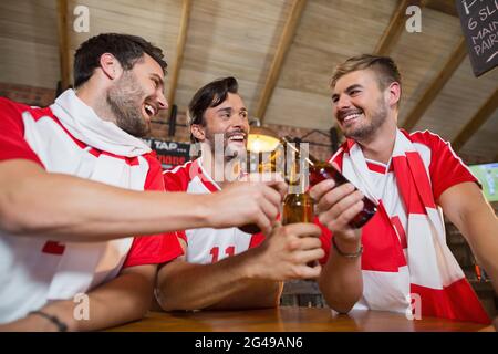 Fröhliche männliche Freunde, die Bierflaschen toasten Stockfoto
