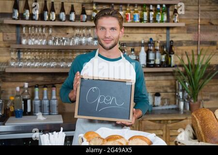 Porträt von lächelnden Kellner halten Tafel mit Schild "geöffnet" Stockfoto
