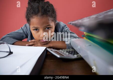 Nahaufnahme eines Mädchens, das vorgibt, als Geschäftsfrau auf dem Schreibtisch zu sitzen Stockfoto