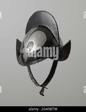 Morion Helm mit extrudierter Lilie. Morion Helm, Eisen, geschwärzt mit blank extrudierter Lilie, aus zwei Hälften. Hohe Helmlampe mit hohem Kamm der Rand ist tabellarisch. Rund um die Basis des Helmglobus acht Goelkoperenrosetten. Das Ventil weist auf der Vorder- und Rückseite stark steigende Punkte auf. Der Rand des Ventils ist flaven. Auf der linken und rechten Seite auf der Helmkugel kupferfarbene Nieten, mit denen der Kinngurt innen befestigt ist. Der Lederkinngürtel besteht aus zwei Lederreifen, deren Enden aneinander befestigt sind. Jedes Band hat fünf Metallplatten, die jeweils an zwei ri befestigt sind Stockfoto