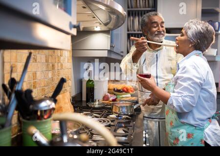 Mann, der Frau füttert, während er in der Küche steht Stockfoto