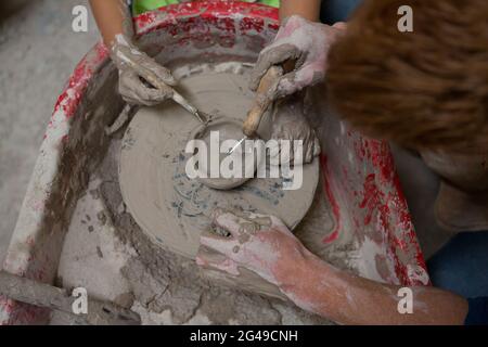 Männlicher Töpfer, der Mädchen beim Formen eines Tones hilft Stockfoto