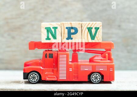 Fire ladder truck hold letter block in word NPV (Abbreviation of net present value) on wood background Stockfoto