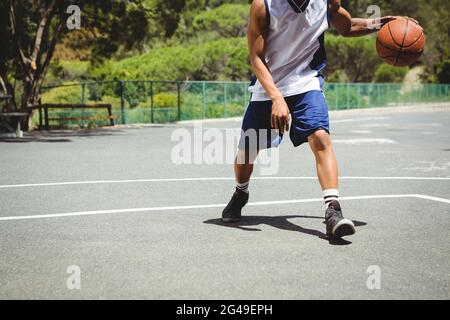 Niedriger Abschnitt des männlichen Teenagers, der Basketball praktiziert Stockfoto