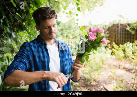 Mann trimmt Blumen mit Schneidescheren im Garten Stockfoto