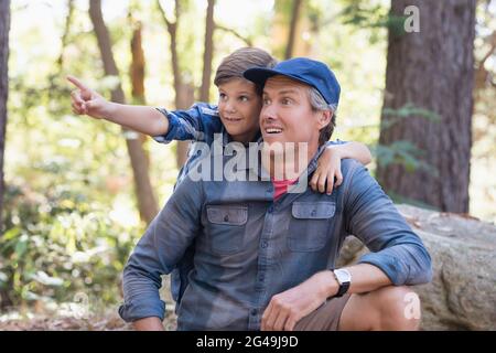 Neugieriger Junge, der dem Vater im Wald etwas zeigt Stockfoto