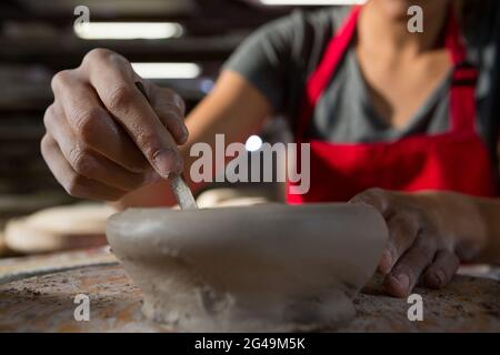 Weiblicher Töpfer, der eine Schüssel mit Handwerkzeug formt Stockfoto