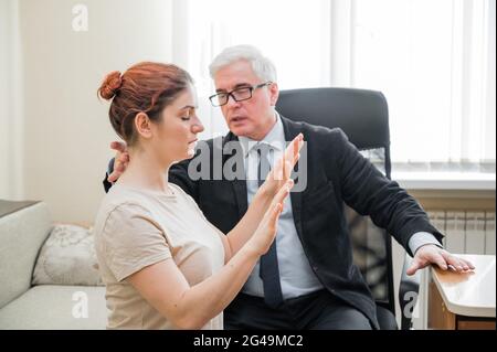 Reifer grauhaariger Mann hypnotisiert kaukasische Frau während der Hypnotherapie-Sitzung. Der Psychologe verwendet alternative Behandlungen für das Unterbewusstsein Stockfoto