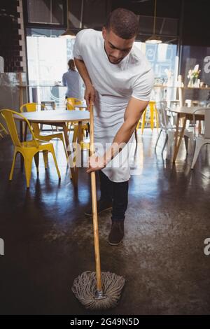 Der Kellner wischt den Boden im Café Stockfoto