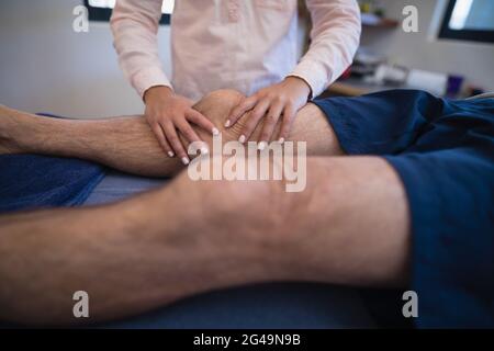 Ärztin massiert Knie des Patienten Stockfoto