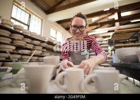 Porträt einer Frau, die Becher an der Arbeitsplatte überprüft Stockfoto