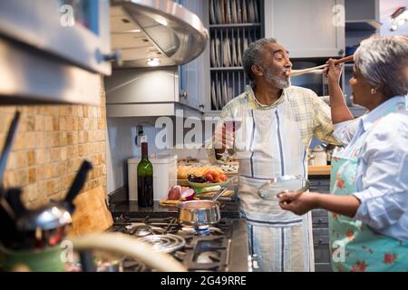 Frau, die Mann füttert, während sie in der Küche steht Stockfoto