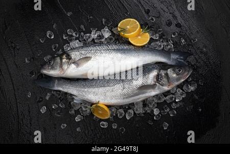 Seevang Fisch auf Eis auf schwarzem Steingrund, Draufsicht Stockfoto