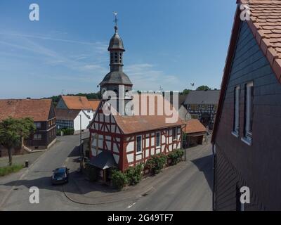 Dannenrod, Deutschland. Juni 2021. Die kleine Dorfkirche aus dem Jahr 1707 hebt sich mit ihrer Fachwerkfassade façade von den Häusern in Dannenrod ab. Der weitere Bau der Autobahn A49 hat auch zu einigen tiefen Spaltungen unter den Bewohnern des kleinen Dorfes Dannenrod geführt. (To dpa: 'Permanenter Streit um A49 belastet Dörfer - 'der Zorn könnte nie verblassen') Quelle: Boris Roessler/dpa/Alamy Live News Stockfoto