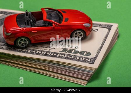 Ein Fragment des amerikanischen Dollars ist auf dem Tisch zu sehen, auf dem sich ein Spielzeugauto befindet. Stockfoto