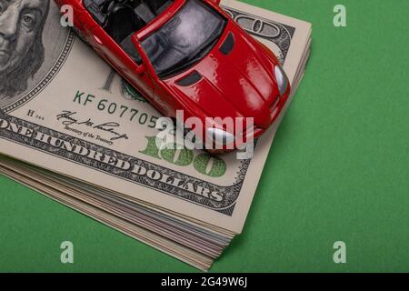 Ein Fragment des amerikanischen Dollars ist auf dem Tisch zu sehen, auf dem sich ein Spielzeugauto befindet. Stockfoto