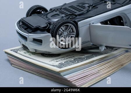 Ein Fragment des amerikanischen Dollars ist auf dem Tisch zu sehen, auf dem sich ein Spielzeugauto befindet. Stockfoto