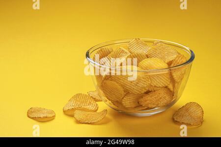 Geriffelte Kartoffelchips in der Schüssel auf gelbem Hintergrund Stockfoto