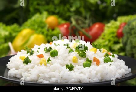 Gekochter Reisbrei, serviert mit Kräutern und Gemüse Stockfoto