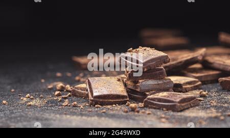 Schokoriegel auf schwarzem Schieferhintergrund mit Kakaopulver Stockfoto