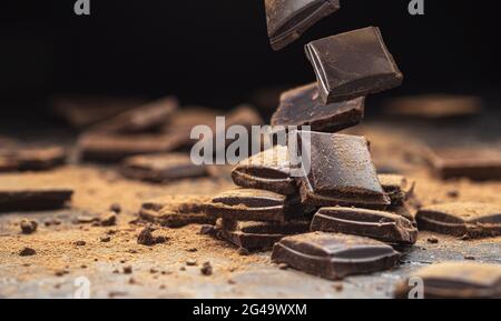 Fallende zerbrochene Schokoriegel auf schwarzem Hintergrund Stockfoto