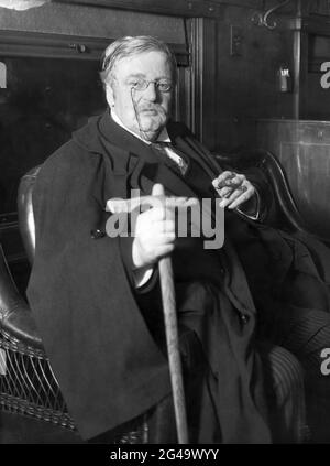 Der britische Schriftsteller G.K. (Gilbert Keith) Chesterton (1874-1936) sitzt mit Umhang, Schwertstock und Zigarre im Mai 1931. (UK) Stockfoto