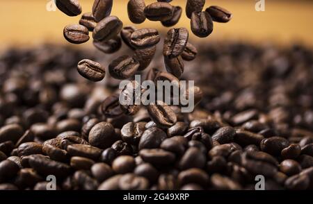 Fallende geröstete Kaffeebohnen auf dunklem Hintergrund Stockfoto