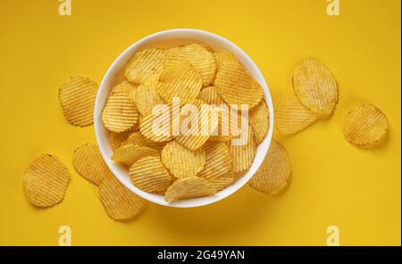 Geriffelte Kartoffelchips in der Schüssel auf gelbem Hintergrund Stockfoto