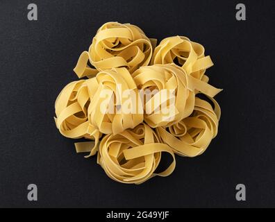 Rohe fettuccine Pasta isoliert auf schwarzem Hintergrund, Draufsicht Stockfoto