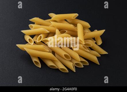 Rohe Penne rigate Pasta isoliert auf schwarzem Hintergrund Stockfoto